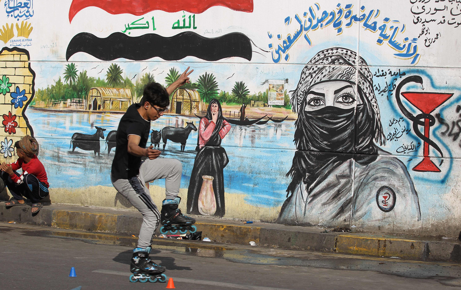 An Iraqi youth rollerblades past graffiti murals drawn by anti-government protesters in Baghdad's Tahrir Square; January 17, 2020. Photo: Ahmad al-Rubaye/AFP